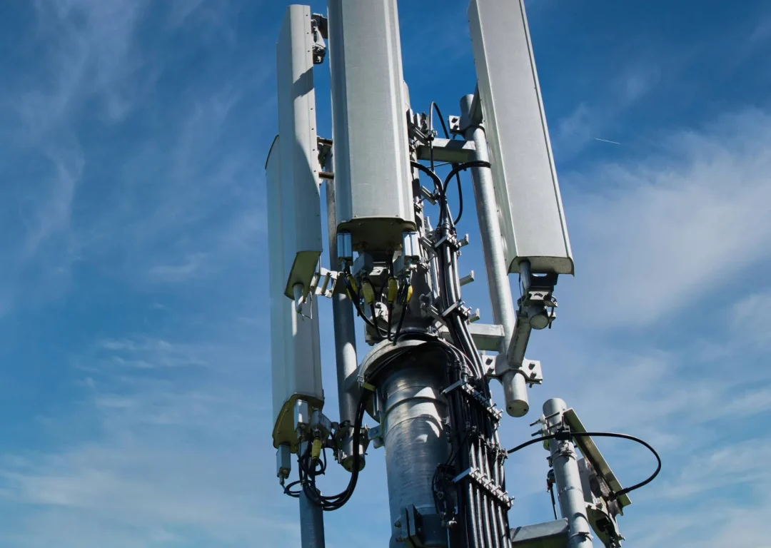A 5G tower set against a clear blue sky.