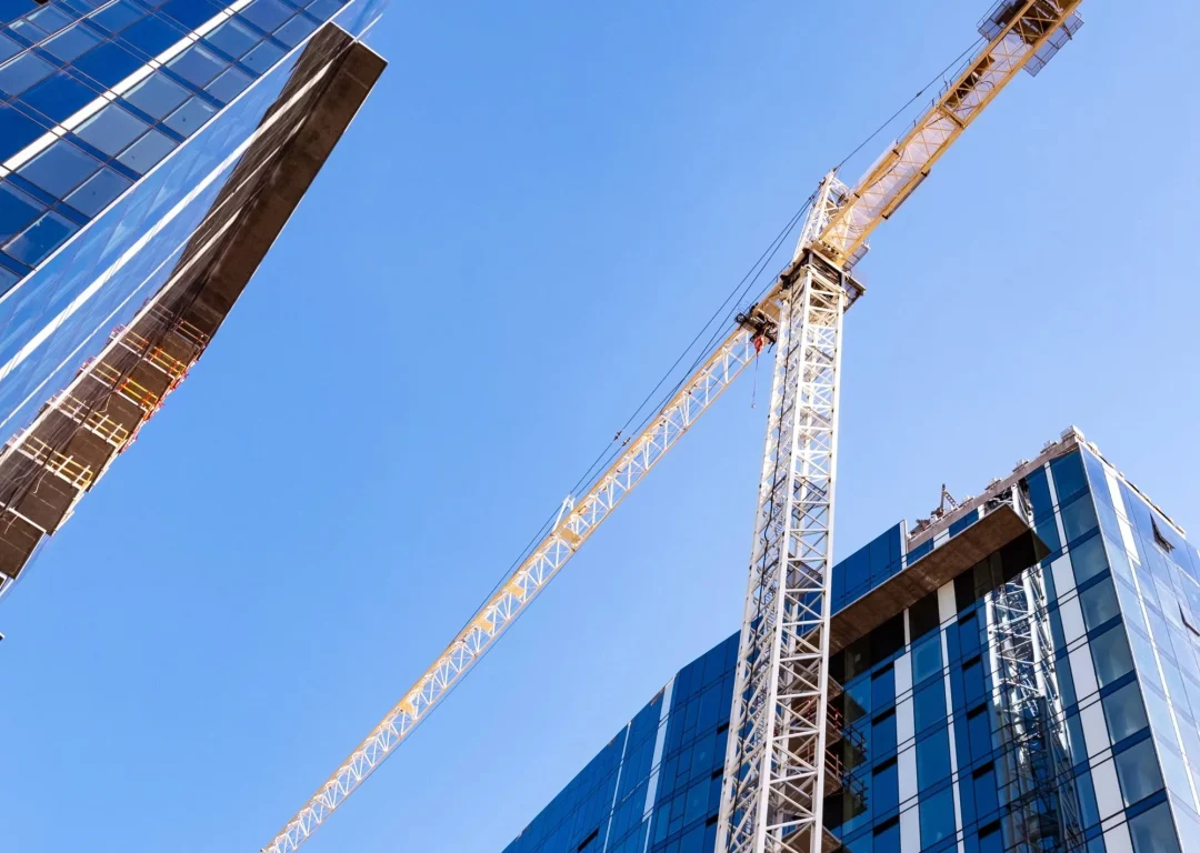 A large yellow crane between two skyscrapers.