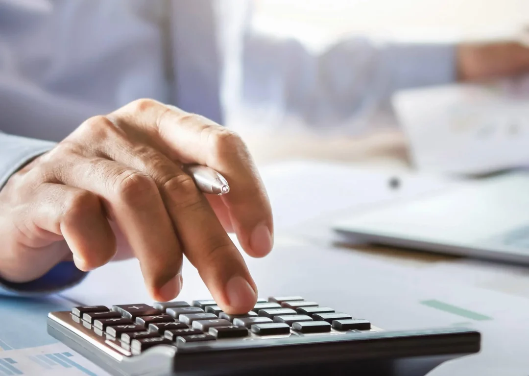 A man in a shirt types on a calculator.