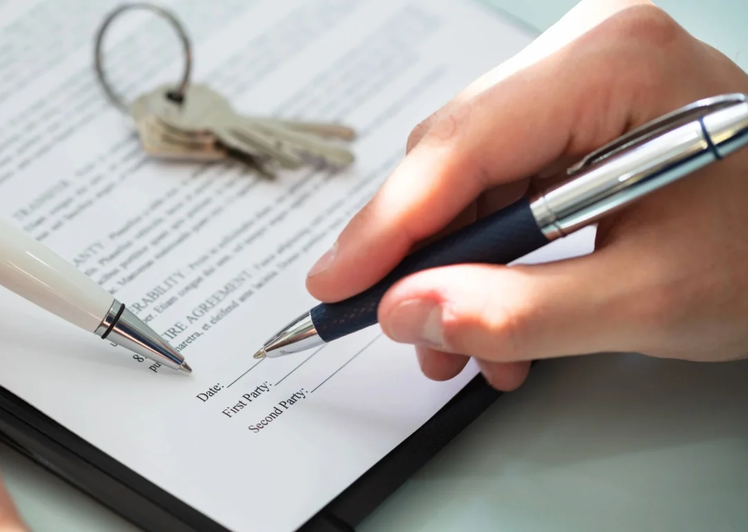 A hand signing a commercial property lease.